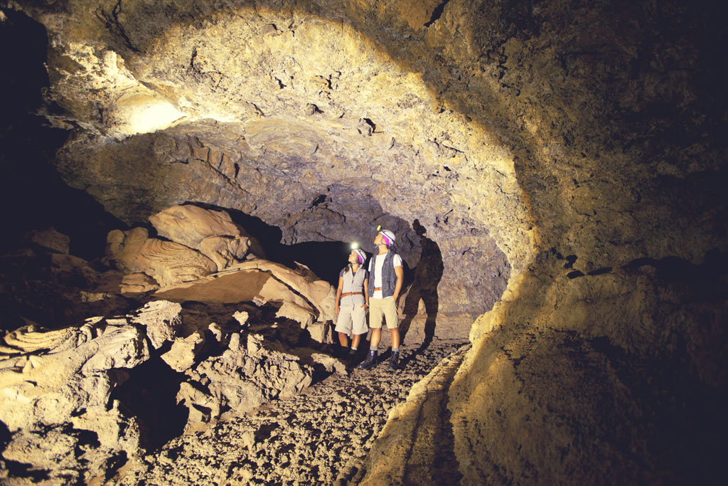 Persone che esplorano la grotta vulcanica a Tenerife con caschi e torce.