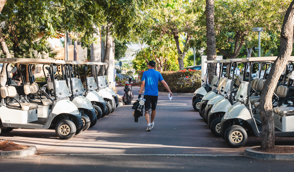 Un uomo cammina tra i golf cart parcheggiati a Tenerife.