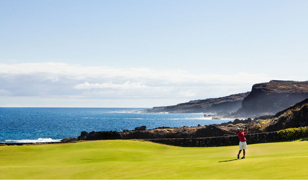 Persona che gioca a golf vicino alla costa di Tenerife con il mare sullo sfondo.