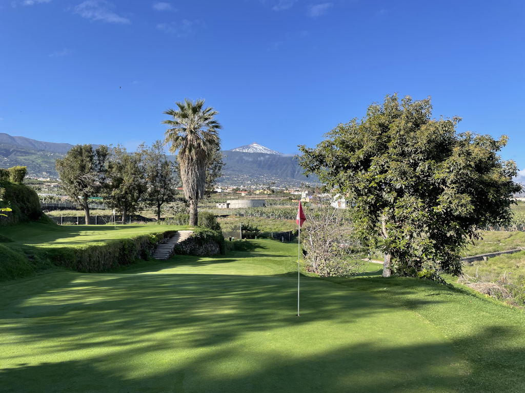 Campo da golf a Tenerife con il Monte Teide sullo sfondo e cieli limpidi.