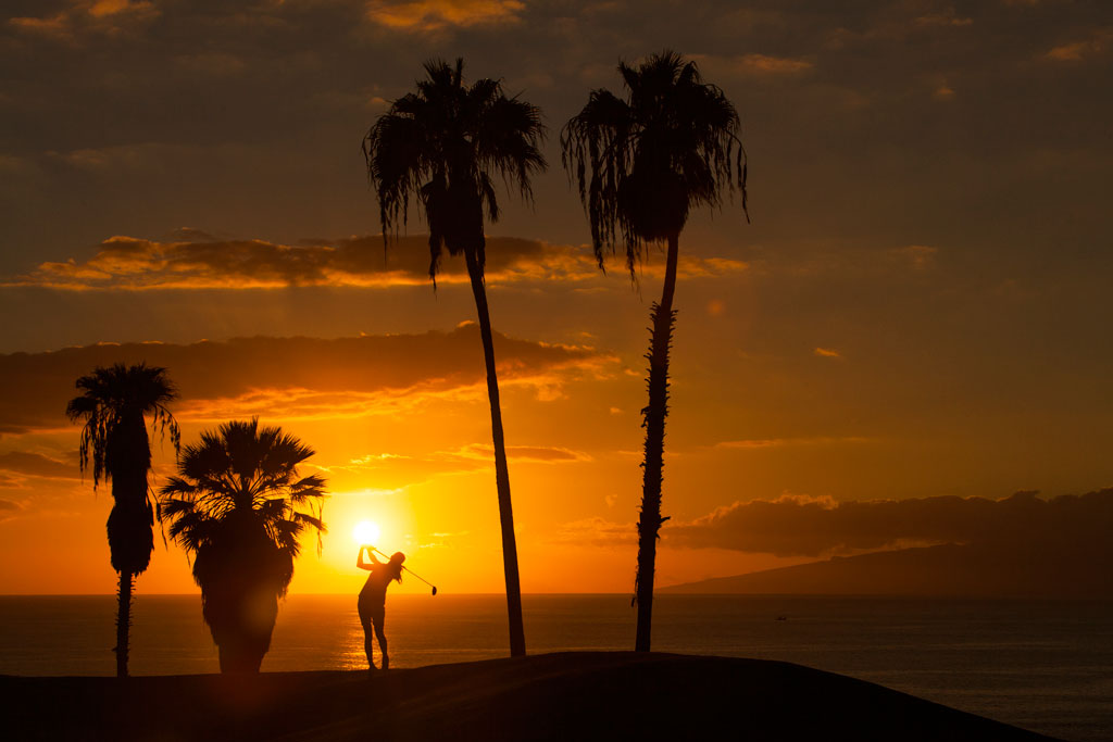 Tramonto, con palme e persone che giocano a golf a Tenerife.