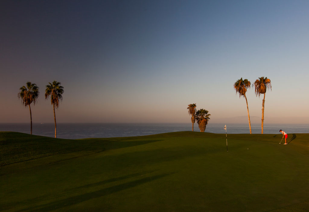 Campo da golf al tramonto con palme e giocatore a Tenerife.