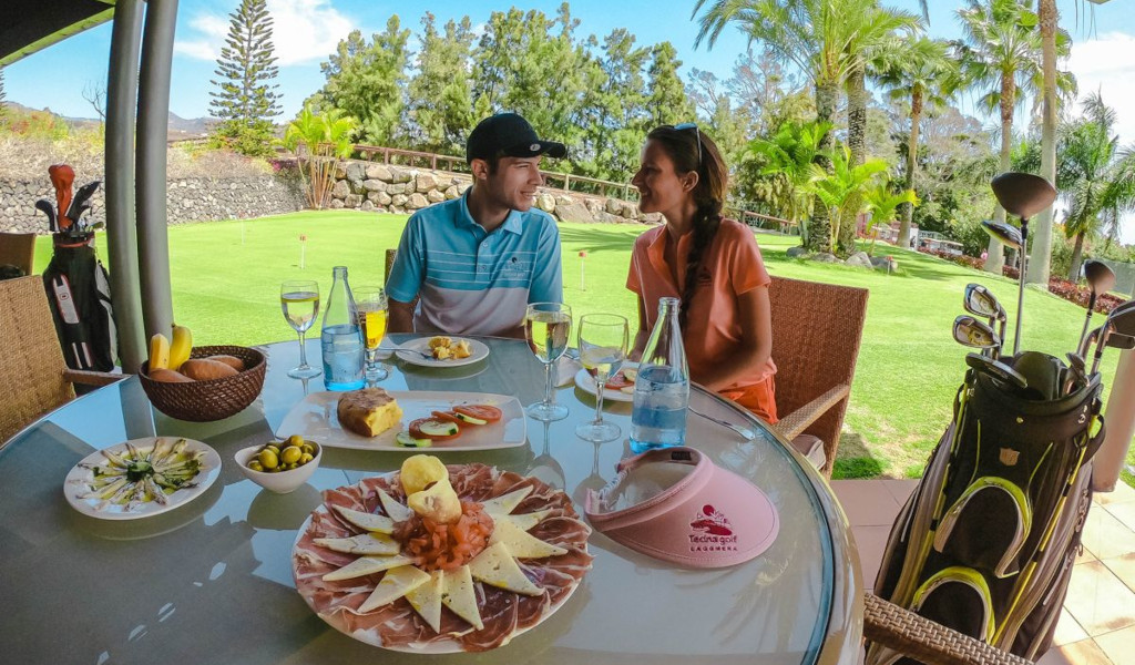Coppia seduta con cibo e club da golf al Tecina Golf, La Gomera, Tenerife.