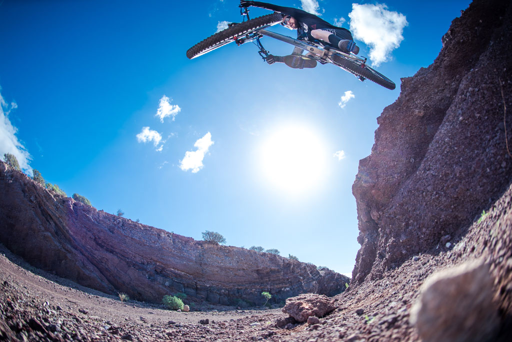Ciclista in salto estremo in un canyon a Tenerife sotto cieli sereni.