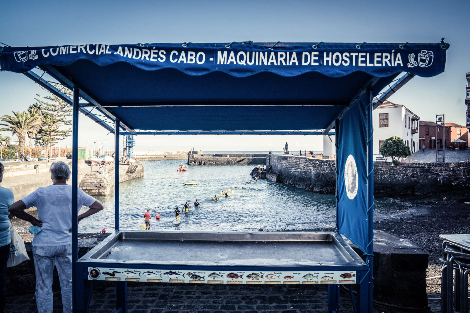 Cabina vuota sul mare a Tenerife, con persone che nuotano sullo sfondo.