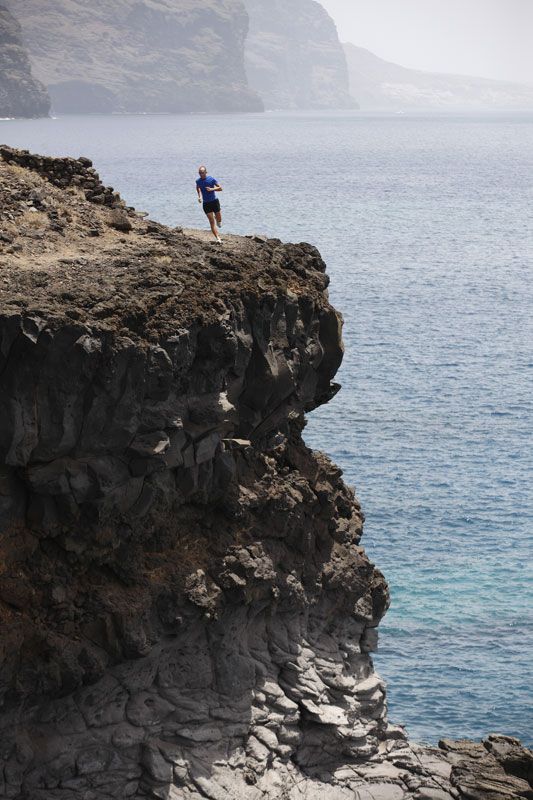 Persona che corre su una scogliera a Los Gigantes, Tenerife, con l'oceano sullo sfondo.