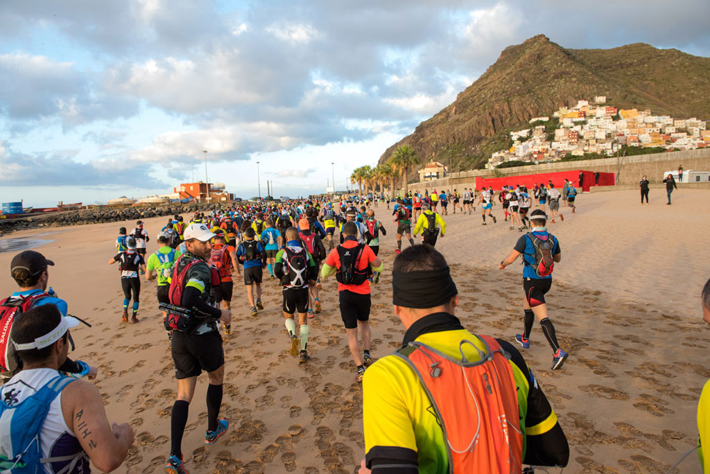 Corridori sulla spiaggia di Las Teresitas a Tenerife durante un evento sportivo.