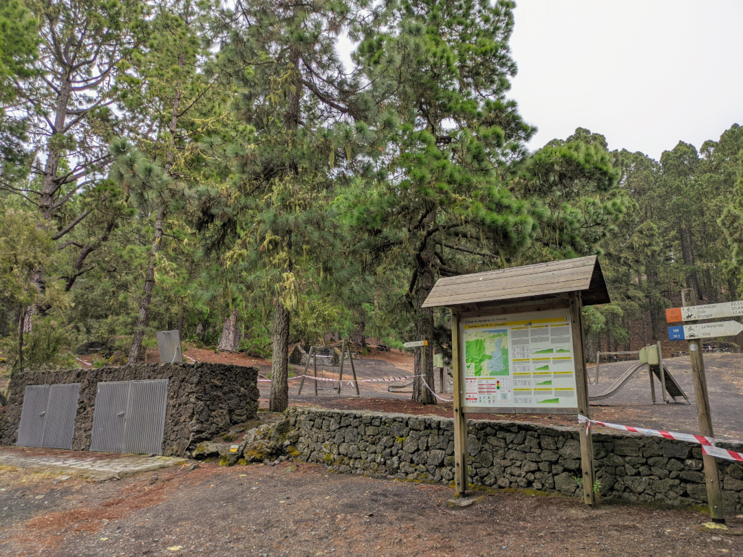 Area ricreativa con mappa e cartelli a La Esperanza, Tenerife, circondata da pini e sentieri.