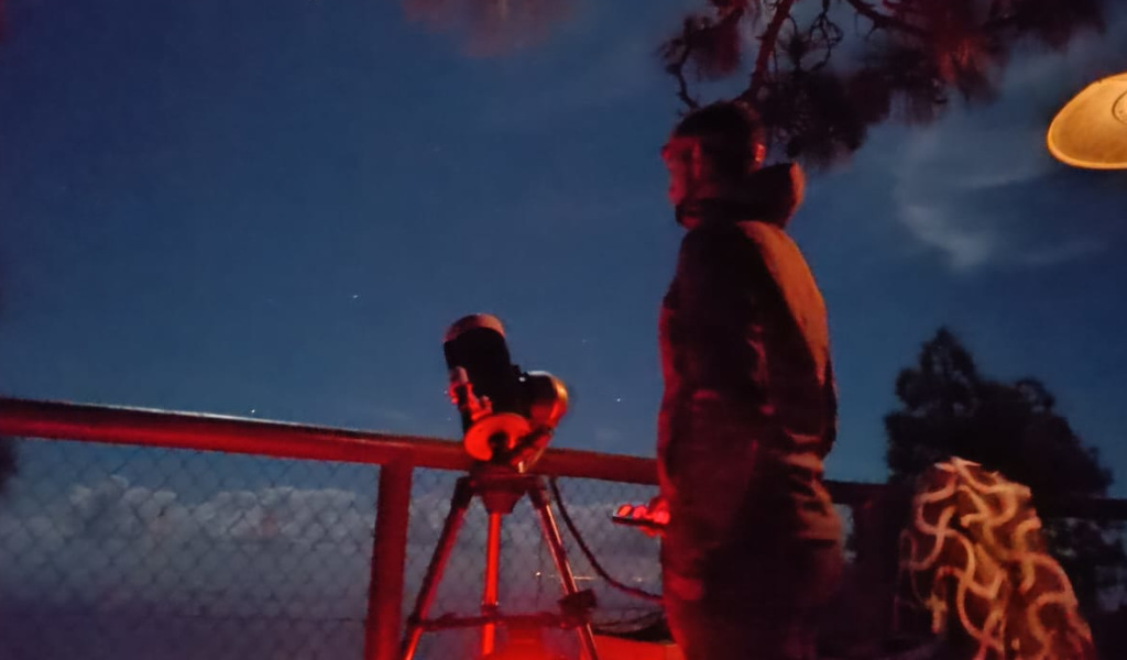 Persona che osserva il cielo notturno con un telescopio, possibilmente a Tenerife.