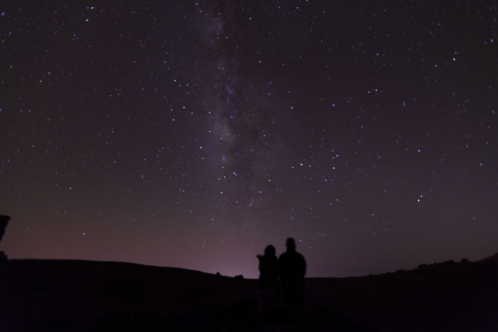 Cielo stellato sopra il Monte Teide a Tenerife con due sagome che osservano.