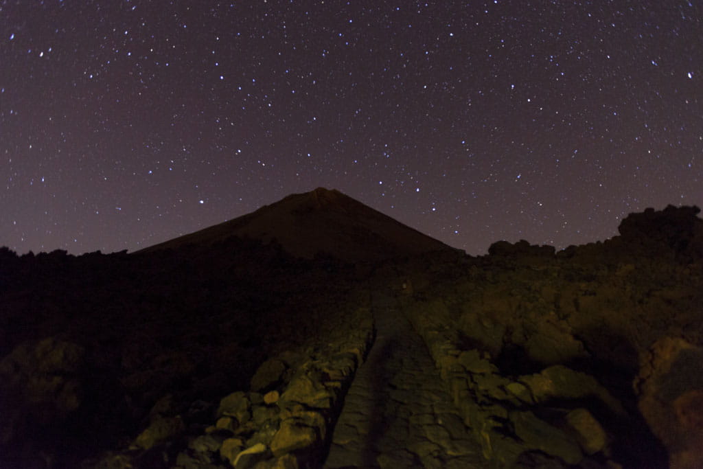 Cielo stellato sul Monte Teide a Tenerife, con sentiero roccioso in primo piano.