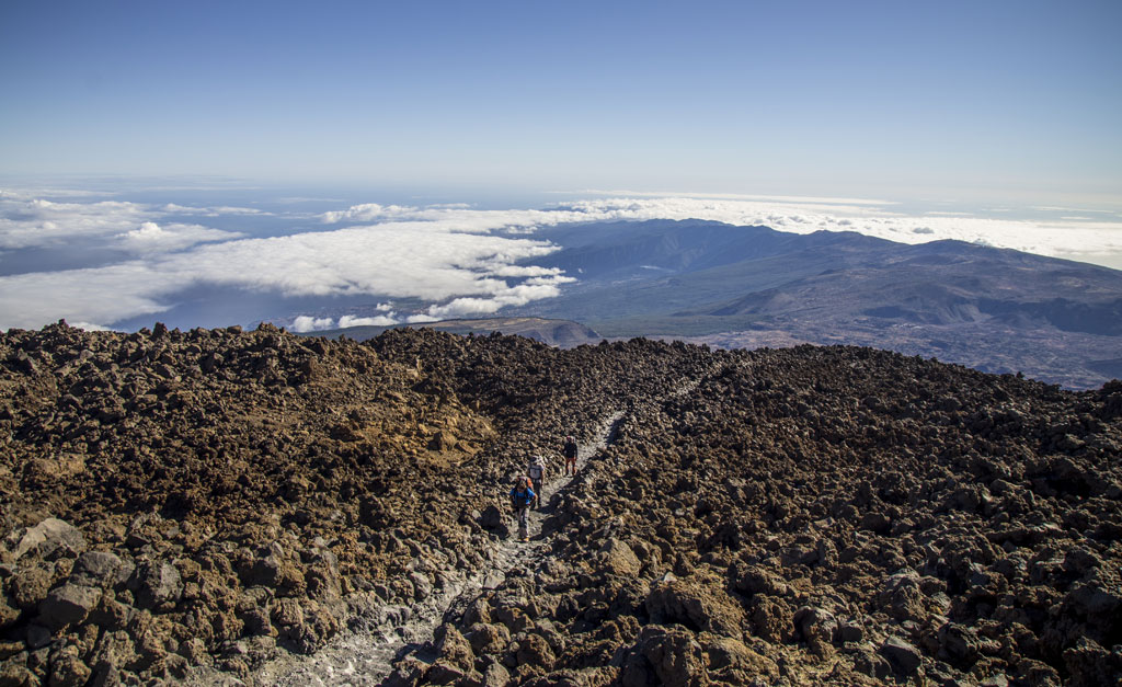Escursionisti sul sentiero del Teide, Tenerife, con nuvole e montagne sullo sfondo.