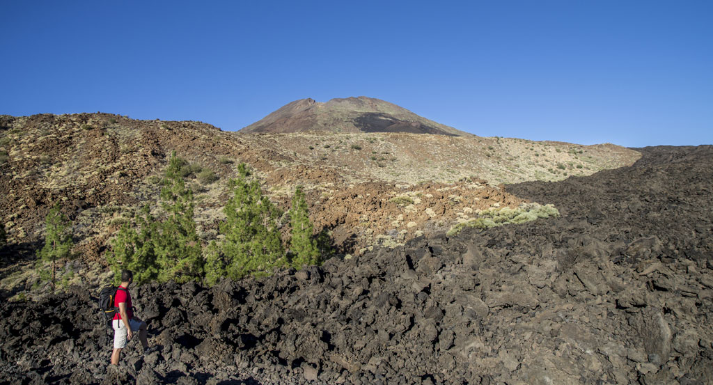 Persona che cammina in paesaggio vulcanico con il Monte Teide sullo sfondo a Tenerife.