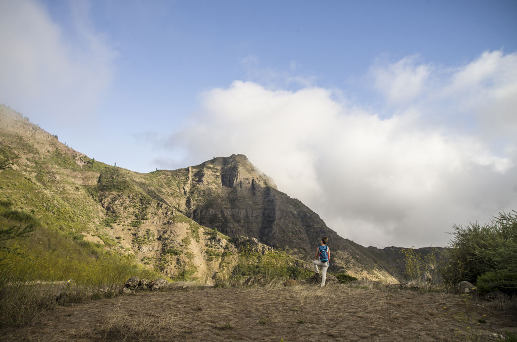 Persona che cammina davanti alle montagne a Tenerife sotto un cielo parzialmente nuvoloso.