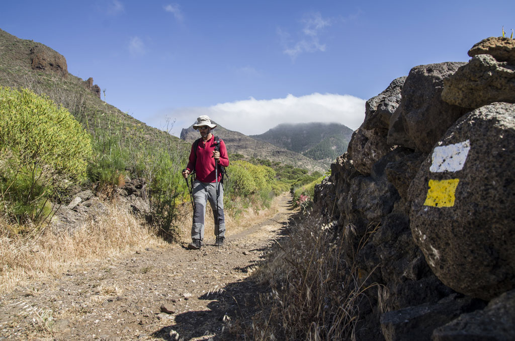 Persona che cammina con un bastone su un sentiero a Tenerife, montagne e segni di roccia.