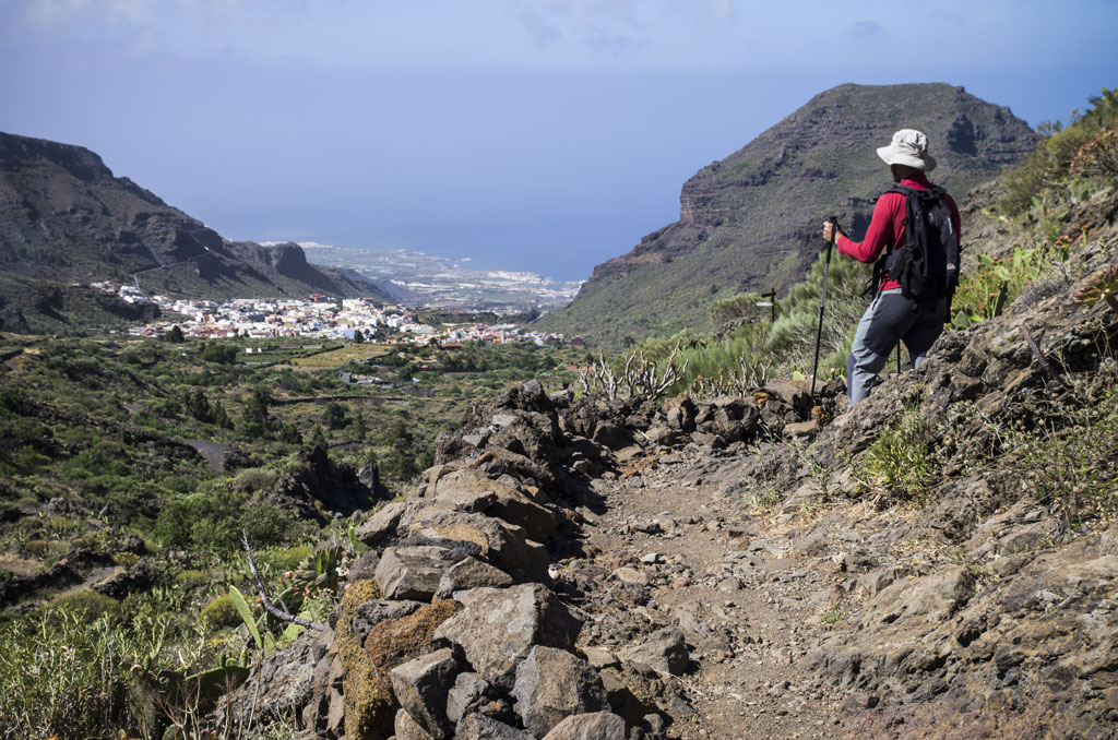 Escursionista con bastoni su un sentiero montuoso, vista su Masca, Tenerife.