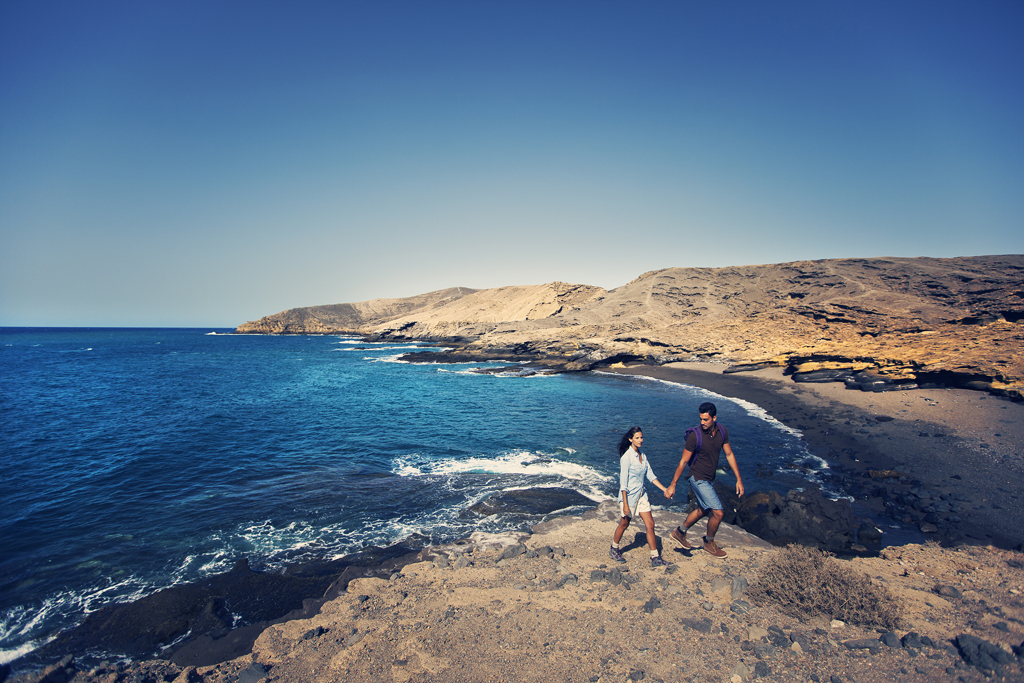 Coppia che passeggia lungo il mare in un paesaggio costiero di Tenerife.