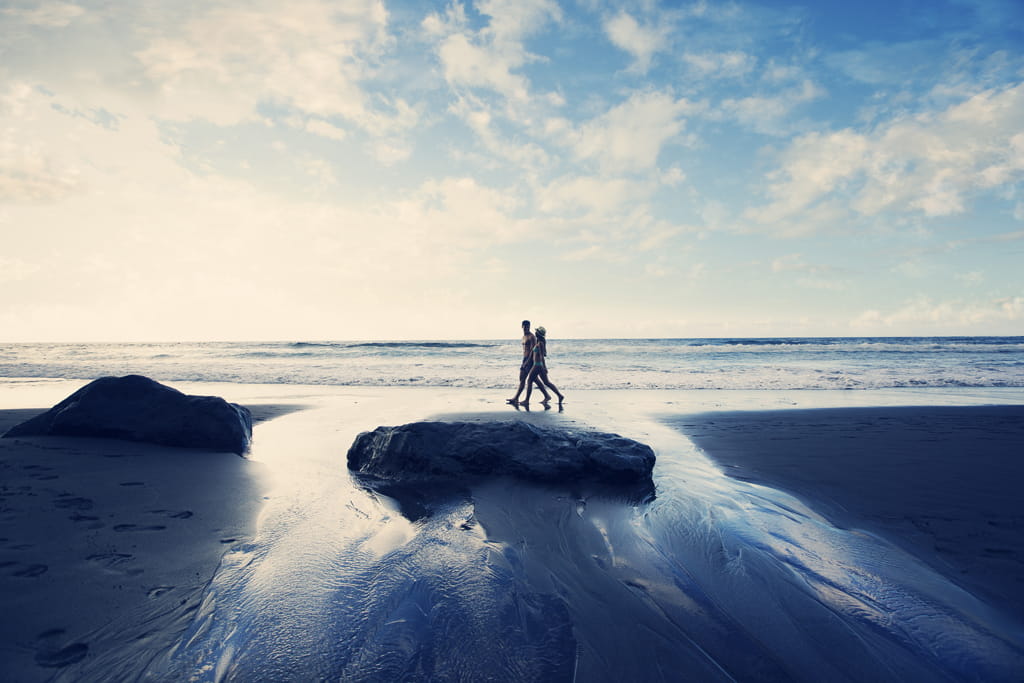 Persone che camminano sulla spiaggia di Tenerife al tramonto.