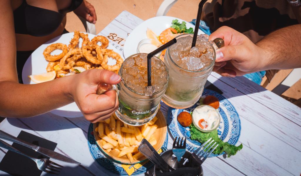 Due persone che brindano su un tavolo con calamari e patate a Tenerife.