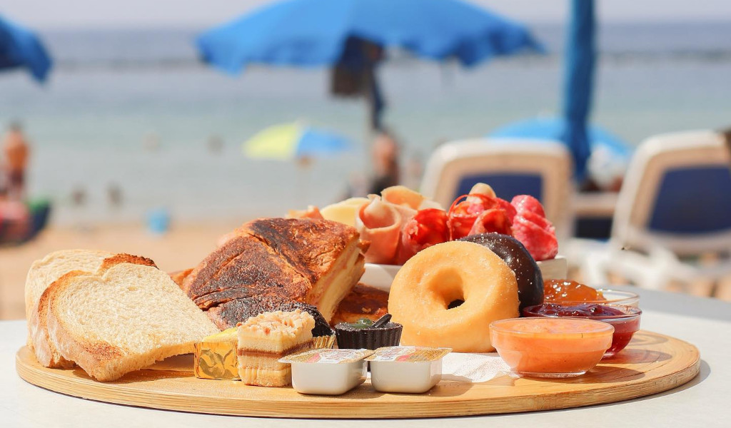 Colazione variegata sulla spiaggia di Las Teresitas, Tenerife, con pane tostato e frutta.