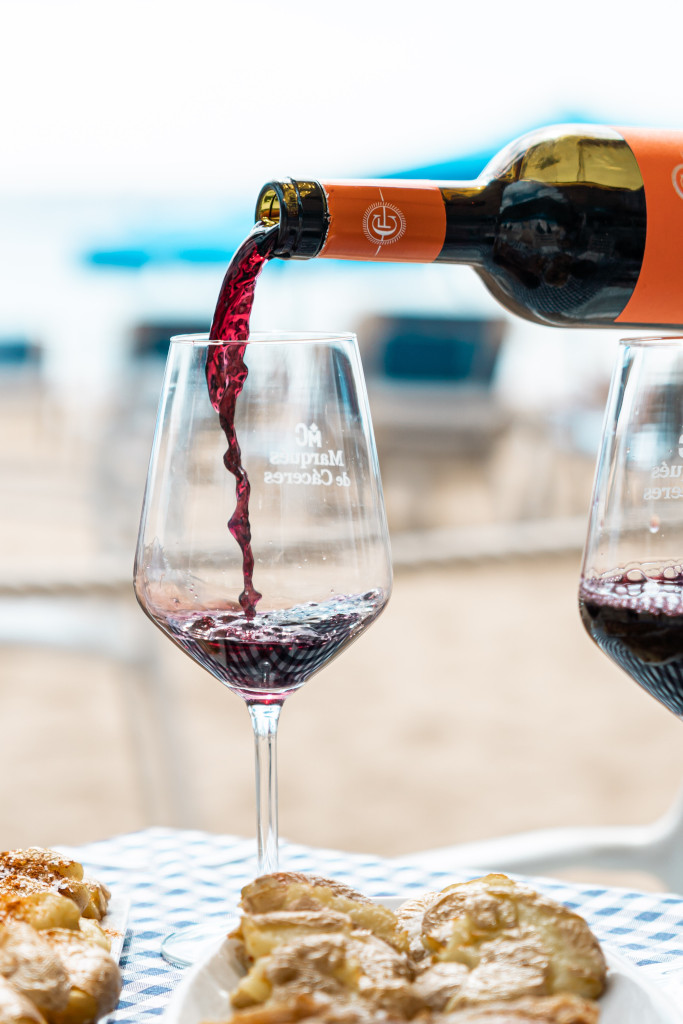 Vino rosso versato in un bicchiere con torte su un tavolo da spiaggia a Tenerife.