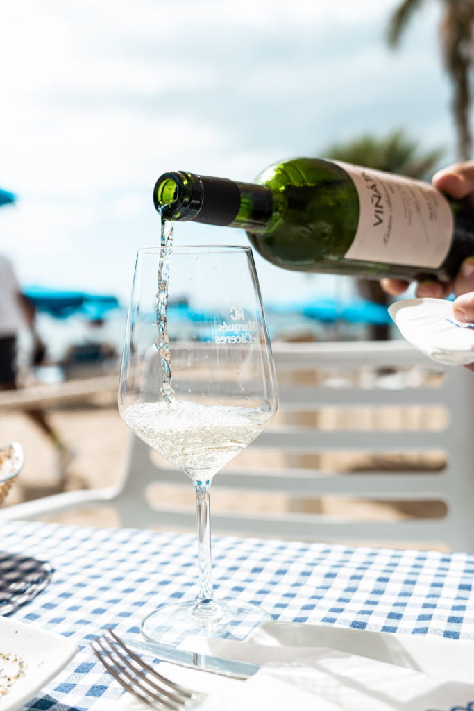 Il vino bianco viene servito in un bicchiere su un tavolo con una tovaglia a scacchi a Tenerife.