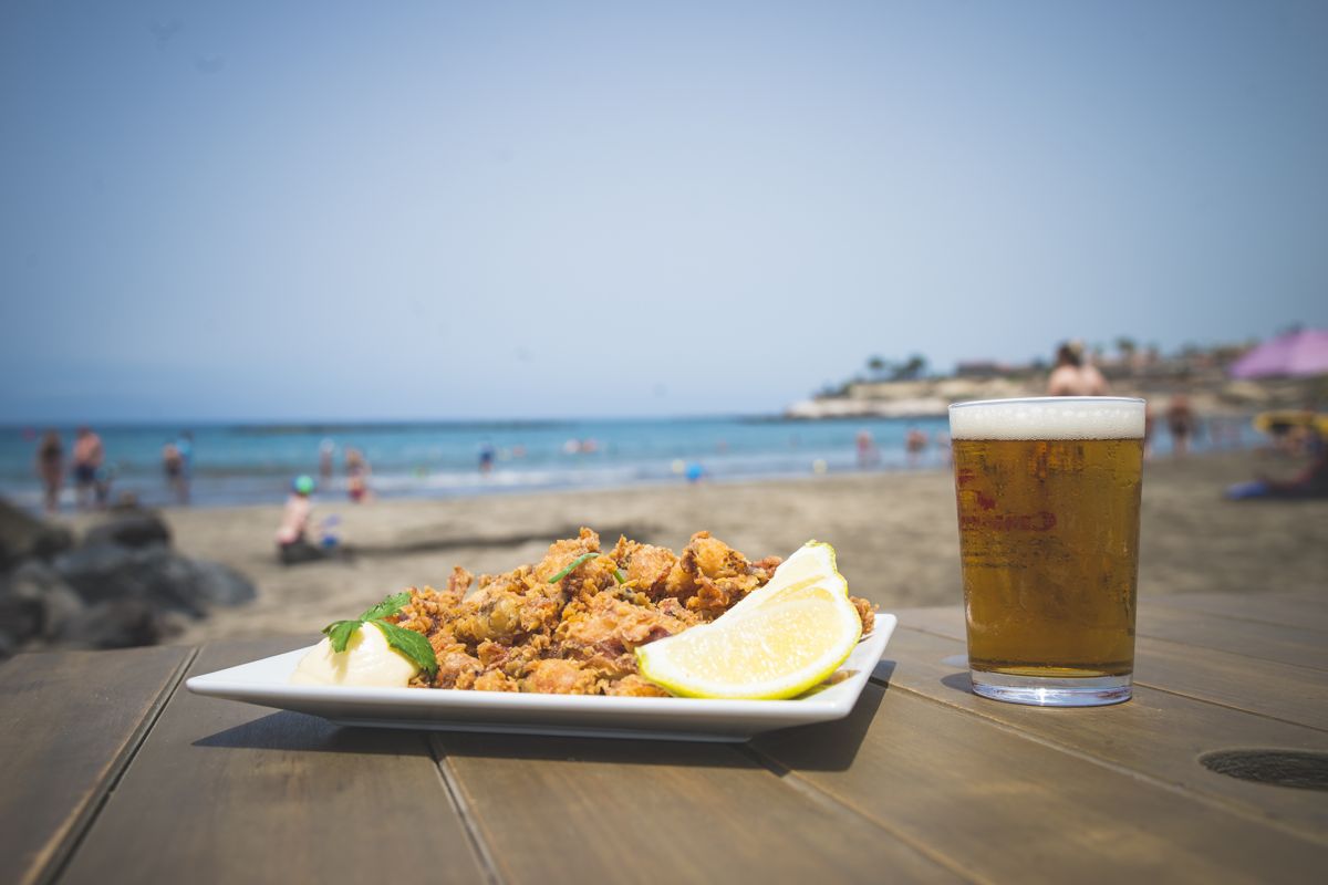 Piatto di cibo e bicchiere di bevanda su un tavolo su una spiaggia a Tenerife.