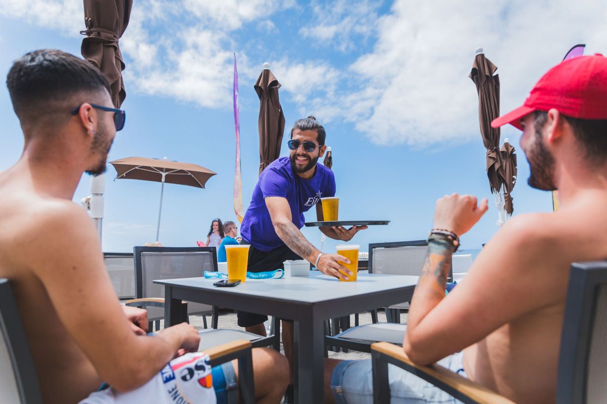 Cameriere che serve birre a due uomini su una terrazza a Tenerife.
