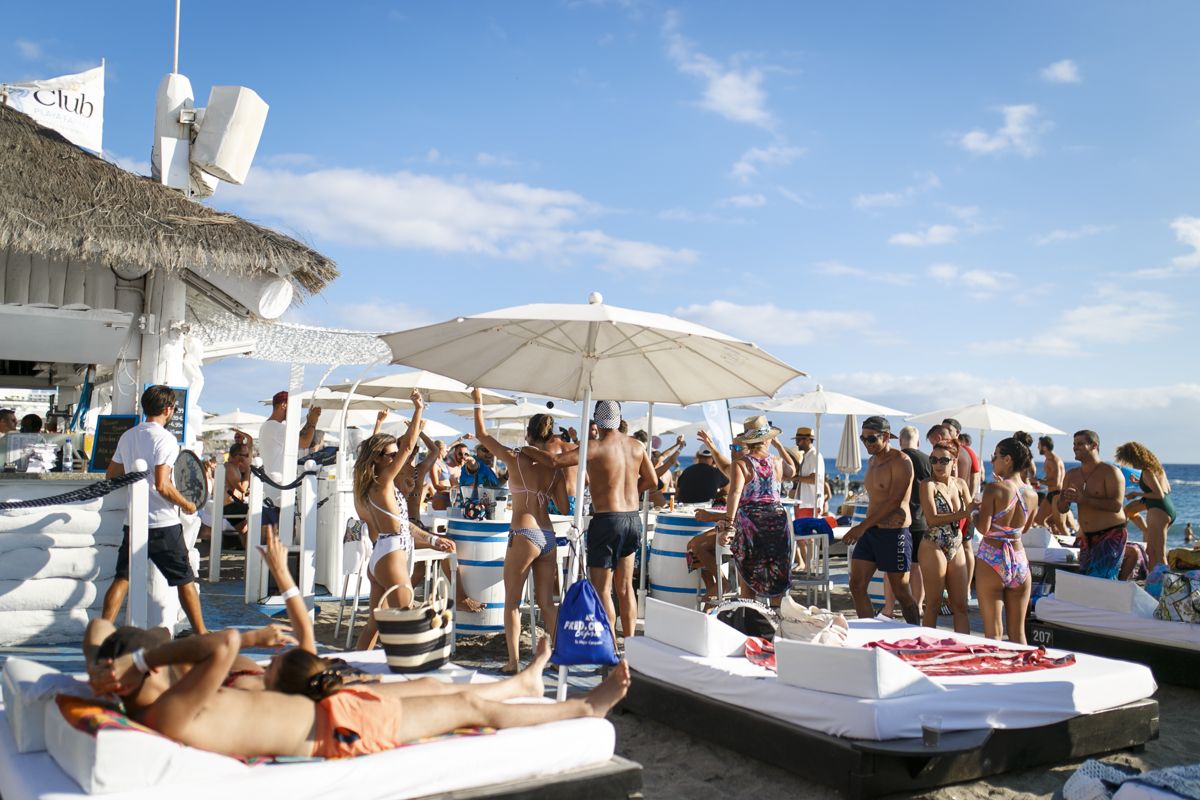 Persone che si godono un beach club a Tenerife sotto ombrelli.