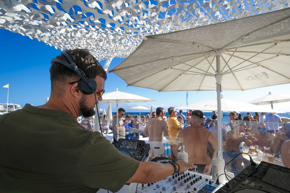 Fare il DJ a un evento all'aperto sulla spiaggia di Tenerife con un pubblico che si diverte.