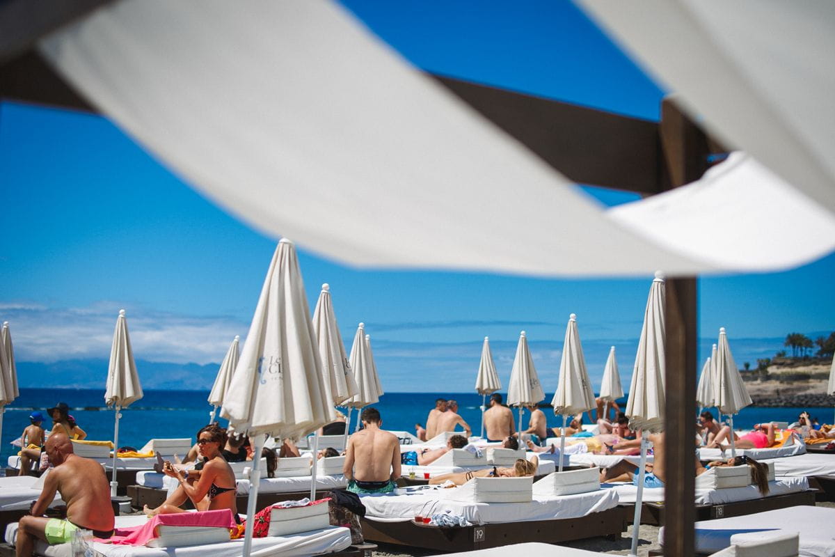 Persone che prendono il sole in amache sotto ombrelloni sulla spiaggia di Tenerife.