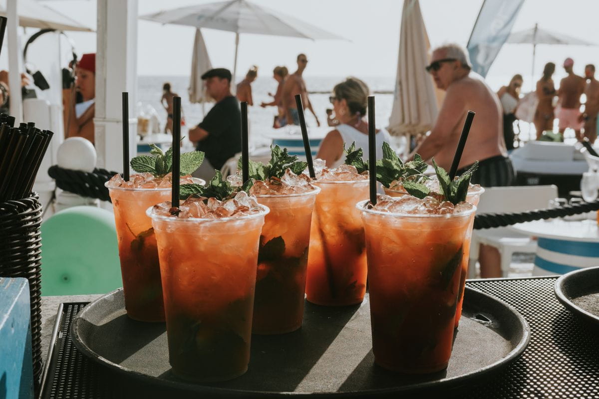 Bicchieri di cocktail con menta e ghiaccio su una spiaggia affollata di Tenerife.