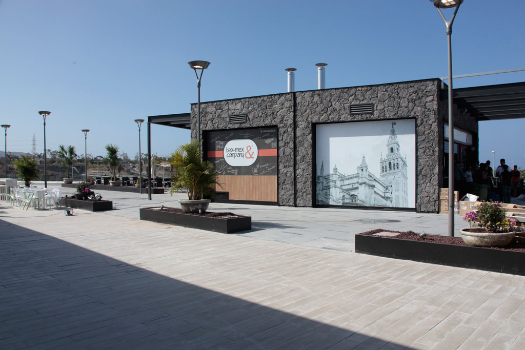 Locali a Tenerife con insegna Tex-Mex & Company e murale di un edificio storico.