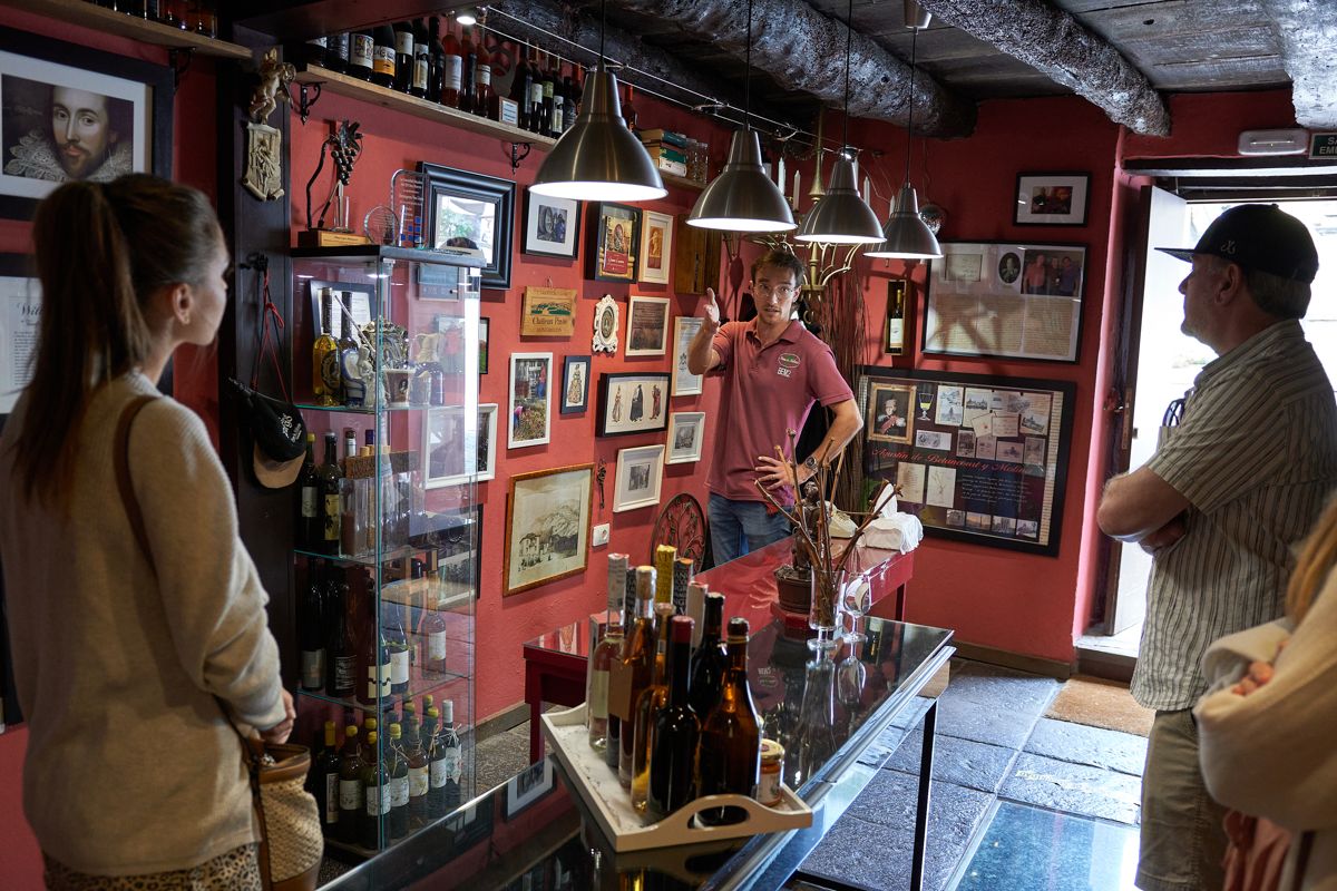 Un uomo che spiega i vini ai turisti, circondato da bottiglie e decorazioni a Tenerife.