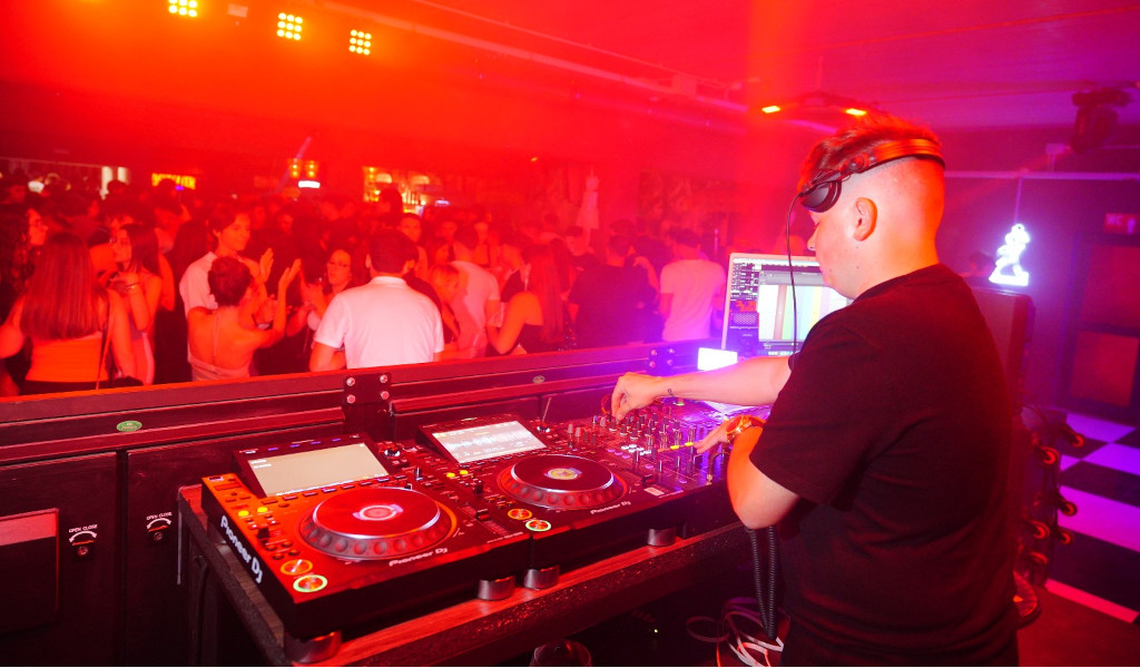 DJ anima festa in un nightclub a Tenerife con luci rosse e pubblico che balla.