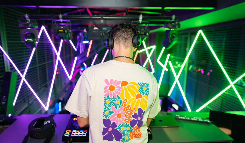 DJ con una maglietta floreale mescola musica nel club di Tenerife con luci al neon.