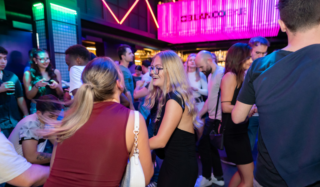 Persone che socializzano e ballano in un nightclub illuminato a Tenerife.