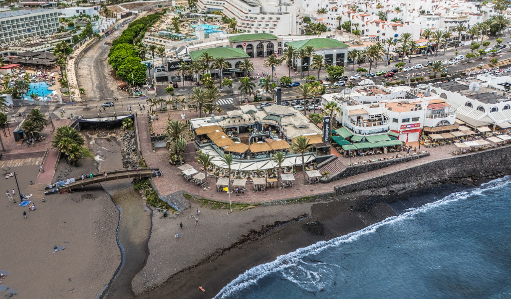 Vista aerea della spiaggia e dell'area urbana di Tenerife con edifici e ristoranti nelle vicinanze.