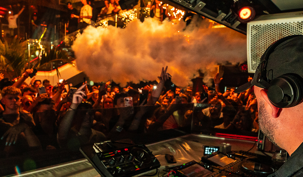 DJ che suona dal vivo davanti a una folla vivace in un locale di Tenerife.