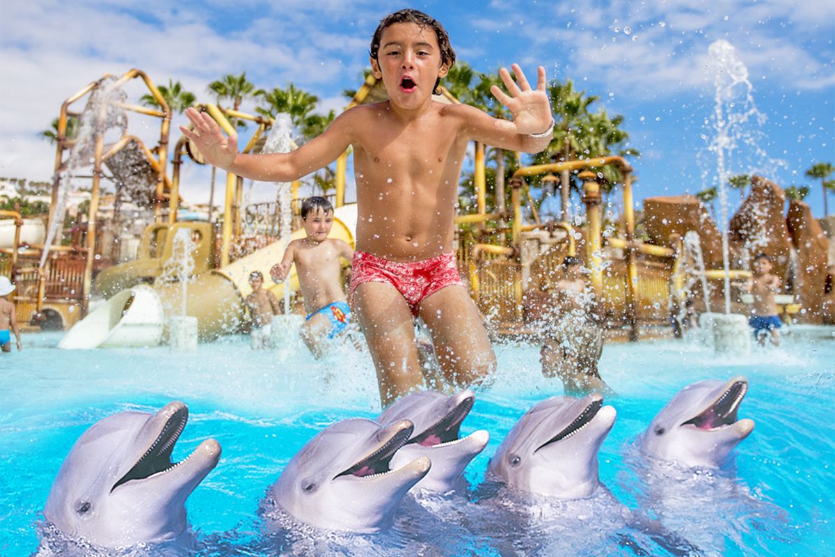 Bambini che giocano con i delfini in una piscina a Tenerife.