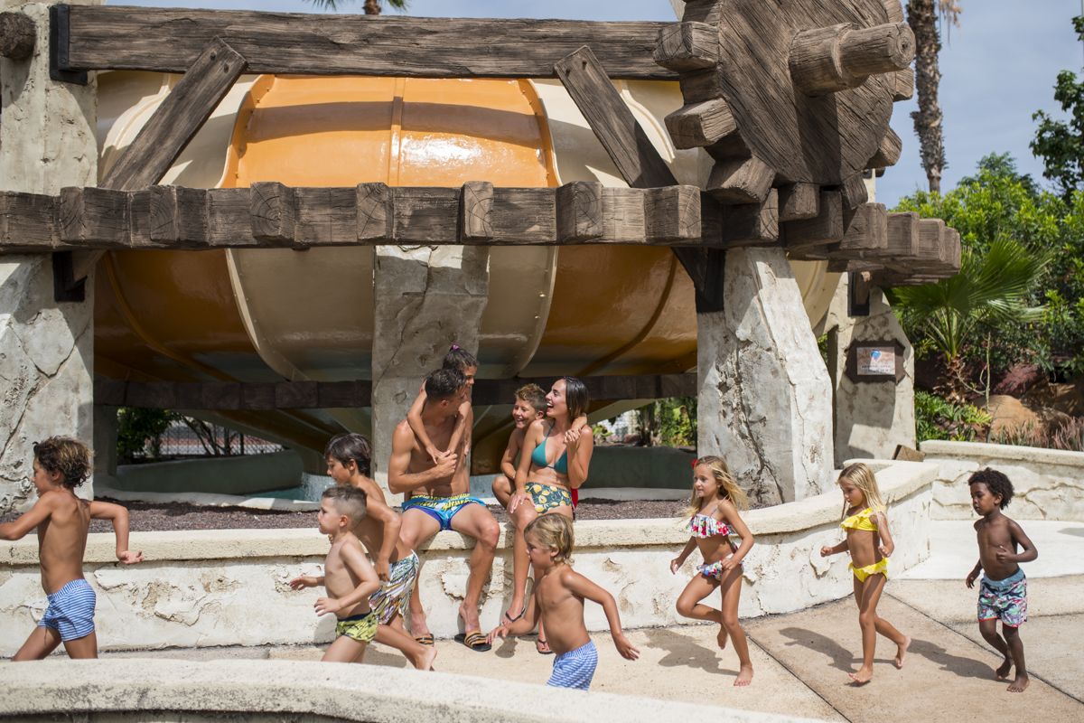 Bambini che giocano nel parco acquatico di Tenerife sotto uno scivolo grande.