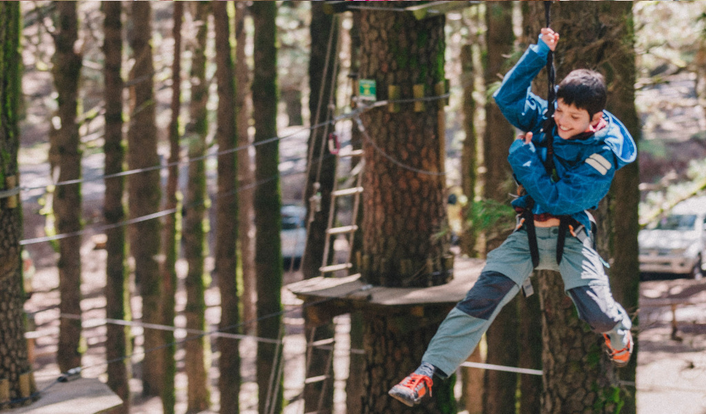 Ragazzo che si diverte con la zip line nel parco avventure a Tenerife.