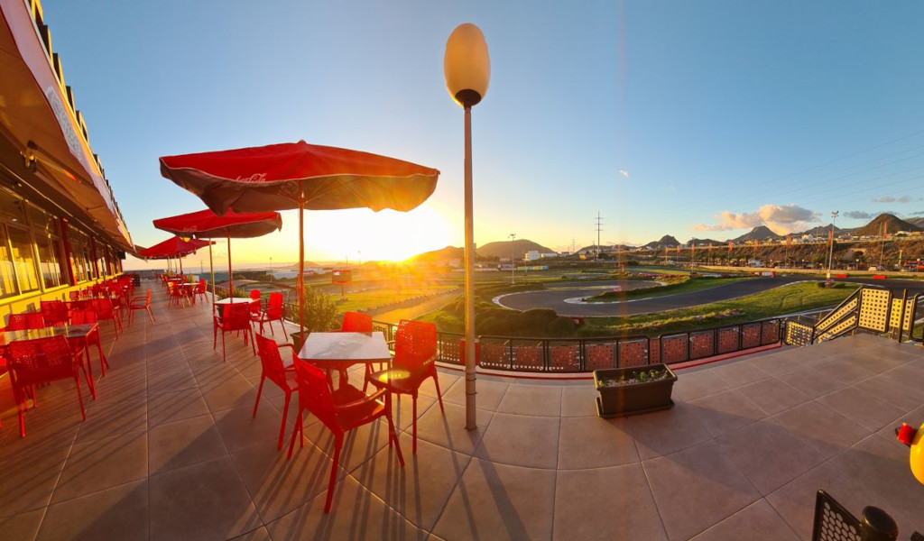 Terrazza ristorante con tavoli rossi e vista al tramonto su un circuito a Tenerife.