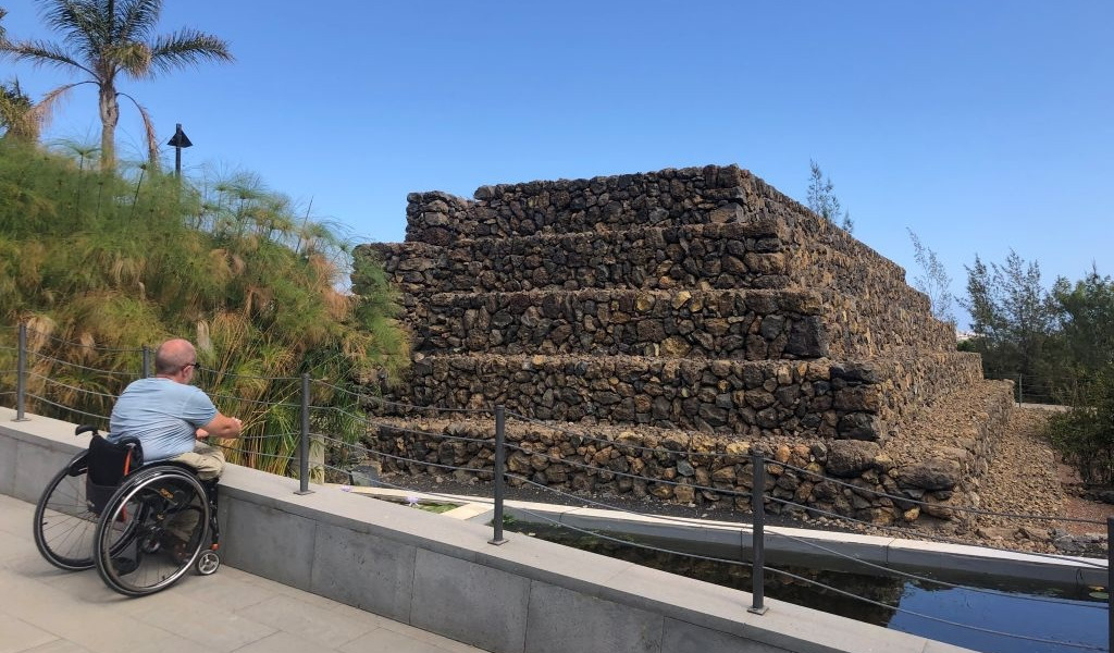 Persona in sedia a rotelle che guarda una piramide a Güímar, Tenerife.