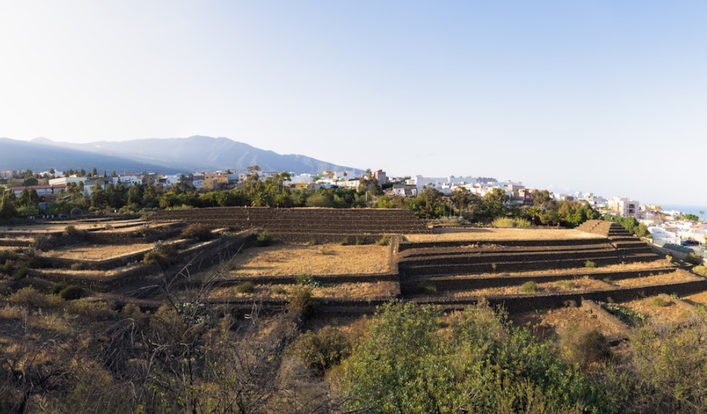 Piramidi di Güímar a Tenerife con montagne e città sullo sfondo.