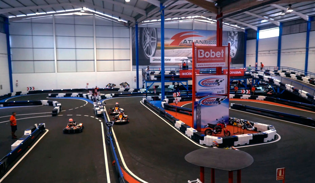 Pista indoor da karting a Tenerife con kart in gara e cartello Bobet.