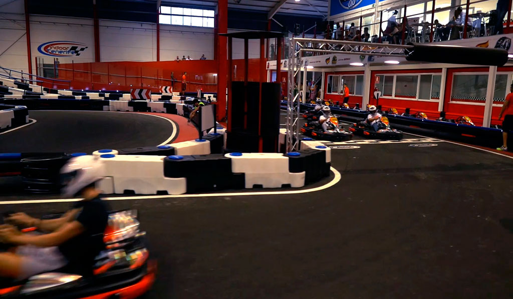 Kart che gareggiano sul circuito indoor di Tenerife con spettatori sullo sfondo.