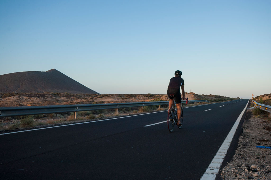 Ciclista sulla strada vicino a un vulcano a Tenerife al tramonto.