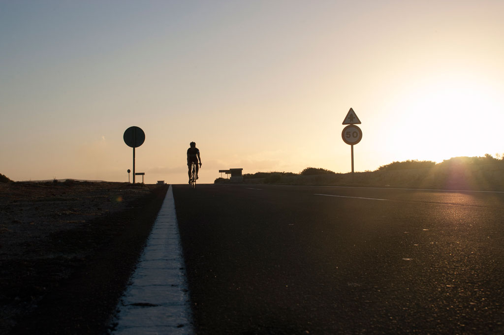 Ciclista al tramonto sulla strada a Tenerife con un limite di 50.
