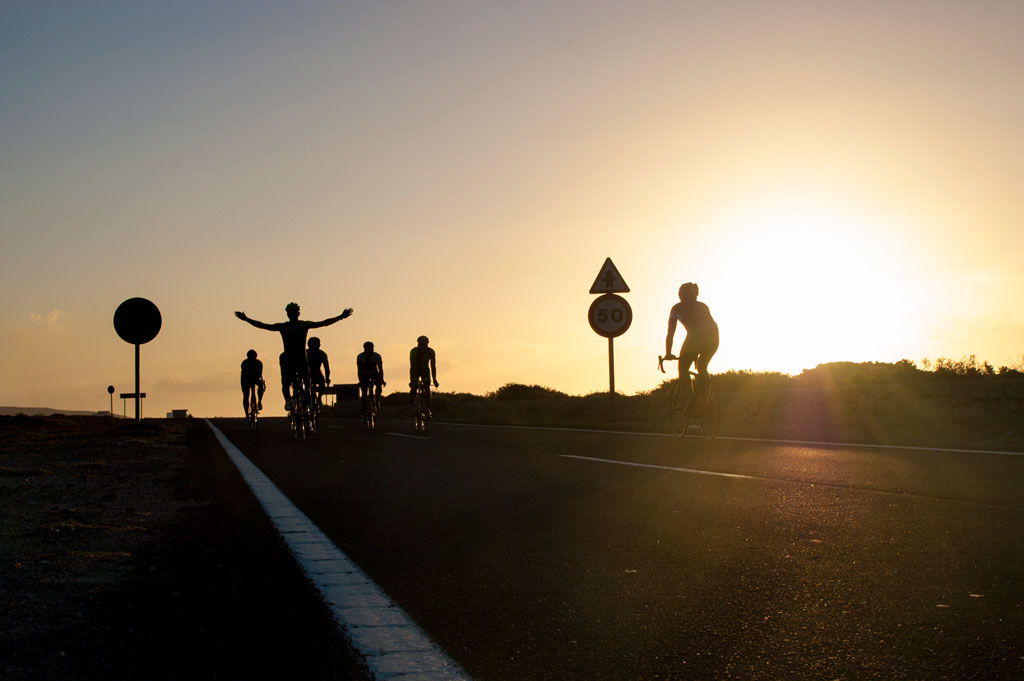 Ciclisti sulla strada al tramonto a Tenerife, accanto a un cartello di velocità 50.